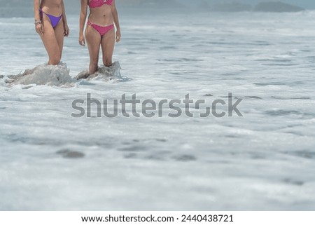 Part of two unrecognizable women in bikini into the sea water