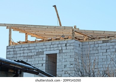  Part Of An Unfinished White Brick House With A Roof With Boards And Wooden Brown Formwork Against A Blue Sky