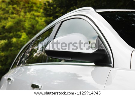 Part of a white car on a forest background