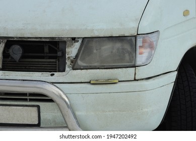 Part Of A White Minibus Car With A Gray Metal Bumper And One Headlight