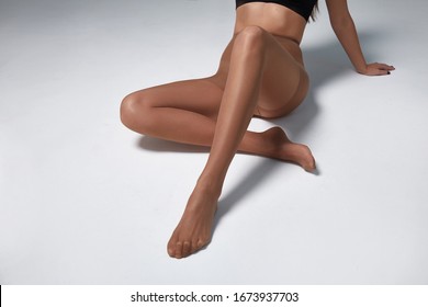Part of woman body perfect shape legs feet skin tan wear stockings, nylons, pantyhose lingerie hosiery hose studio shot. on white background.