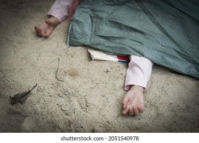 Part of woman or man dead body, closed up hand of dead body was cover by green sag on sand floor.