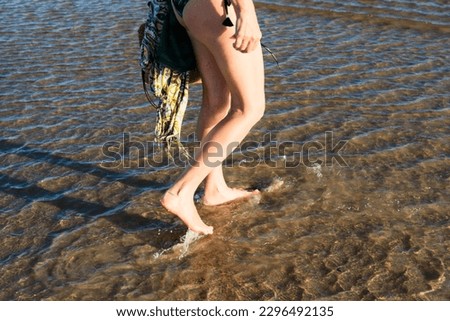 Part of a woman's legs walking in the water at the beach. Guaibim, Valenca, Bahia.