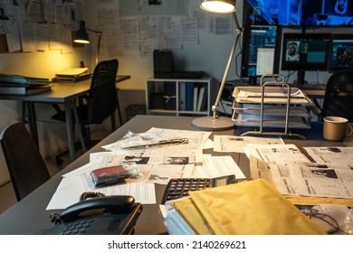 Part of workplace of modern fbi agent with documents, evidences, calculator and telephone on desk lit by lamp in small office