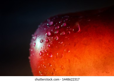 Partial Close Up Of Red Translucent Apple With Drops Of Water In Dark Background Indoors