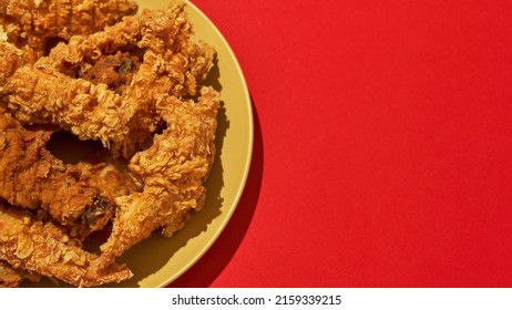 Partial Close Up Of Tasty And Appetizing Baked Chicken Wings And Legs On Plate. Unhealthy Eating And Fast Food. Fried Cooked High-calorie Snack For Leisure. Red Background. Studio Shoot. Copy Space