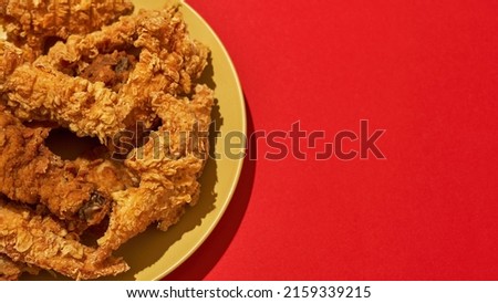 Partial close up of tasty and appetizing baked chicken wings and legs on plate. Unhealthy eating and fast food. Fried cooked high-calorie snack for leisure. Red background. Studio shoot. Copy space