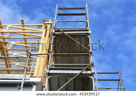 Partial construction on medium office commercial building showing scaffolding and new work against a blue sky, with copy space. 