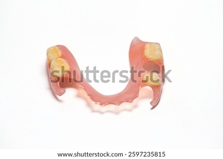 The partial denture is made of flexible materials. Photographed on a white background.