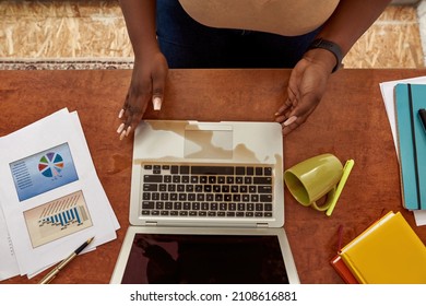 Partial Image Of Black Woman Touching Laptop With Spilled Coffee Or Tea From Cup During Working At Home Workspace. Concept Of Freelance And Remote Work. Top View Of Millennial Girl Sit At Wooden Table