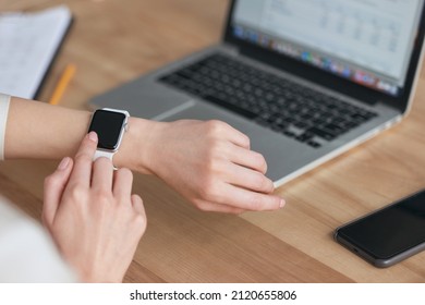 Partial image of businesswoman browsing smartwatch during work at office. Concept of modern successful woman. Idea of business and entrepreneur lifestyle. Girl sitting at table with opened laptop - Powered by Shutterstock