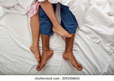 Partial image of legs of black man and woman under blanket on bed. Couple resting at home. Closeness. Concept of domestic lifestyle. Girl wearing pajamas. Guy wearing pants. Top view - Powered by Shutterstock