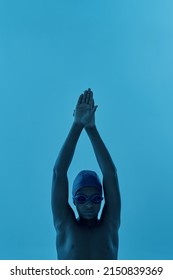 Partial Image Of Serious Black Boy Swimmer In Swim Pose Looking At Camera. Male Youngster Wearing Swimming Cap And Goggles. Modern Child Sportive Lifestyle. Blue Background. Studio Shoot. Copy Space