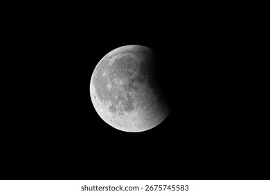 Partial lunar eclipse – full moon with shadow on black sky.