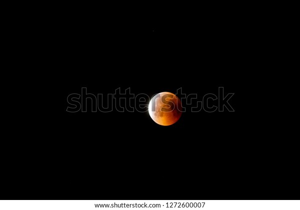 Partial lunar eclipse with orange and\
red colors of moon. eclipse background photo.\
