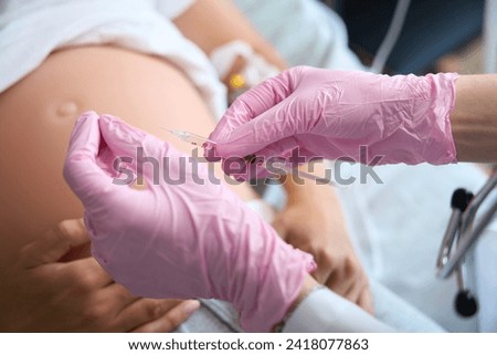 Partial of nurse preparing syringe for injection in pregnant belly of patient