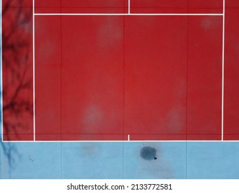 Partial overhead drone view of a red and blue tennis court