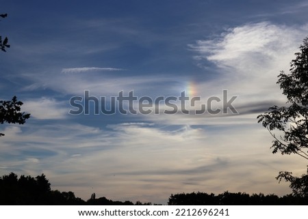 Partial rainbow amongst clouds and blue sky. landscape