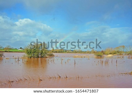 Partial rainbow and blue sky over flooded farm land when the River Leadon burst its banks at Highleadon, near Newent, Gloucestershire, UK