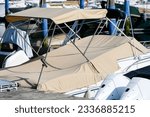 Partial shot close up of beige foldable roof sun shade bikini bimini top sun sail canopy and sport boat motor boat covered with brown canvas in a harbor as a concept for protection from sun wind