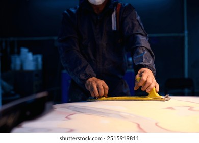 Partial shot of workman in protective suit buffing car part in service station	 - Powered by Shutterstock