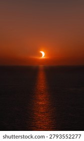 Partial solar eclipse at sunset over the ocean with the sun's reflection on the water of the Mediterranean near Menorca