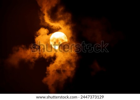 A partial solar eclipse through the clouds as the moon covers about 17% of the sun on April 8, 2024