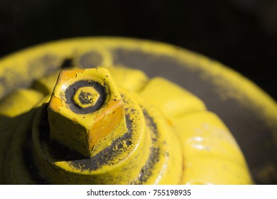 Partial Top Side View of Yellow Fire Hydrant Against Dark Background

