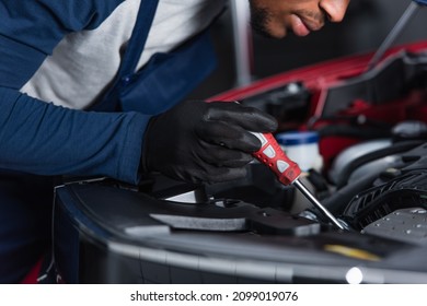 partial view of african american mechanic with screwdriver fixing car engine in workshop
