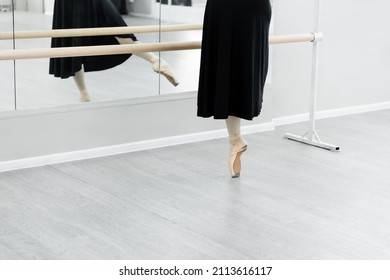 partial view of ballet dancer practicing at barre near mirrors