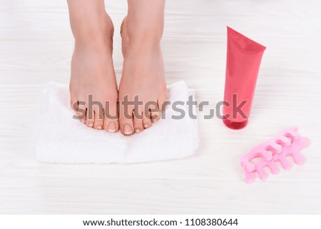 partial view of barefoot woman on towel near toe finger separators and cream container in beauty salon 