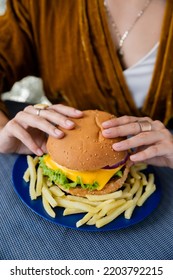 Partial View Of Blurred Woman Holding Delicious Burger Near French Fries On Blue Plate