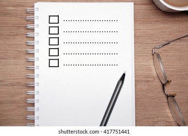 Partial View Of A Book, A Pair Of Glasses, And A Cup Of Coffee. Blank Task List. 