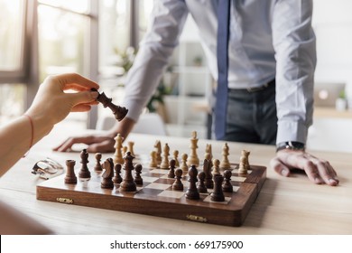 partial view of businessman playing chess with colleague in office - Powered by Shutterstock