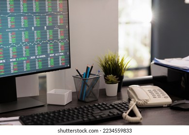 Partial view of computer monitor with financial analysis software for stock market investment risk. Investment specialist desk with work materials on the table early in the morning.