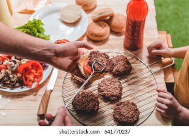 Partial View Of Dad And Son Cooking Meat Burgers Together