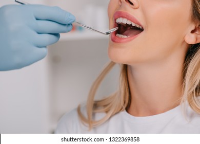 partial view of dentist examining teeth of young woman with mouth mirror - Shutterstock ID 1322369858