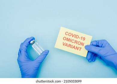 Partial View Of Doctor In Latex Gloves Holding Vaccine Vial And Card With Covid-19 Omicron Variant Lettering On Blue