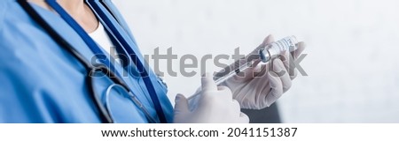 partial view of doctor in latex gloves filling syringe with vaccine, banner