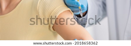 partial view of doctor with vaccine near woman in clinic, banner