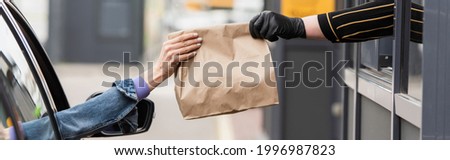 partial view of driver taking takeaway food from seller in latex glove, banner