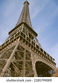 Partial view of Eiffel Tower intricate ironwork against overcast sky