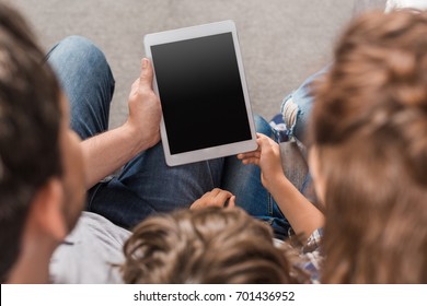 Partial View Of Family Using Digital Tablet At Home