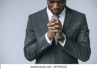 partial view of focused african american businessman praying alone isolated on grey