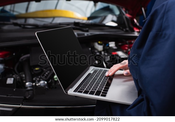 partial view of forewoman with laptop making\
diagnostics of blurred car in\
service