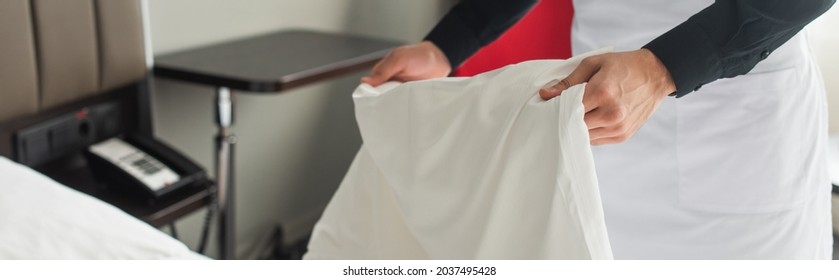partial view of housekeeper changing bedding in hotel room, banner