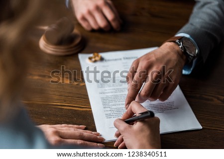 partial view of judge pointing at papers and client signing divorce decree 