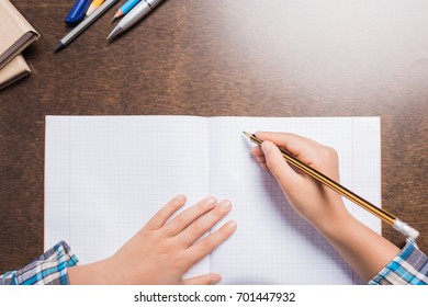partial view of kid writing in notebook while doing homework