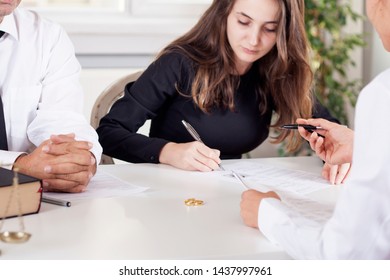 partial view of lawyer and client sitting at table with divorce decree and wedding rings
