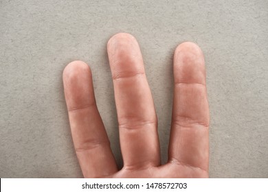 partial view of man showing three fingers on grey background